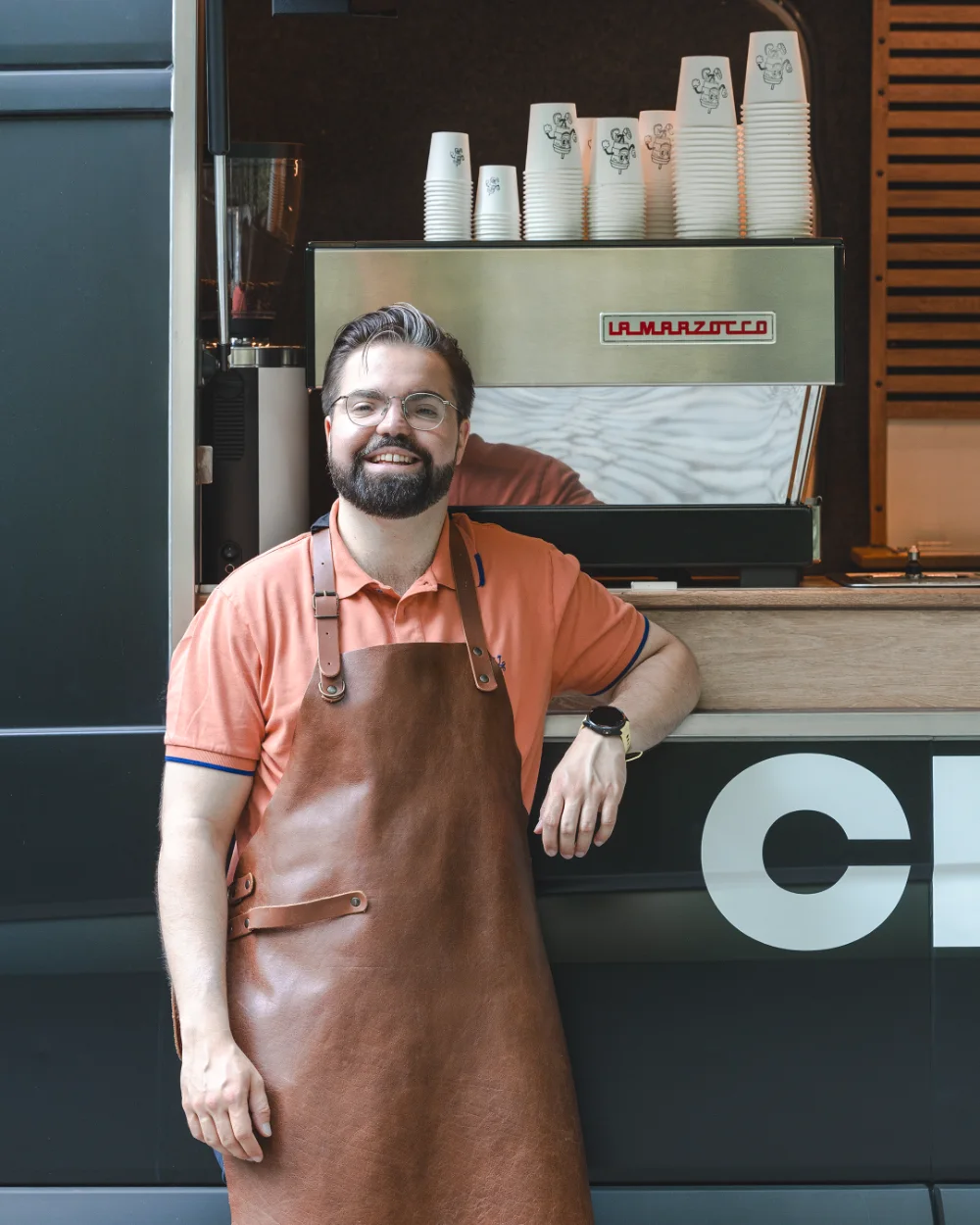 Barista poseert voor La Marzocco espressomachine in mobiele koffiebar food truck